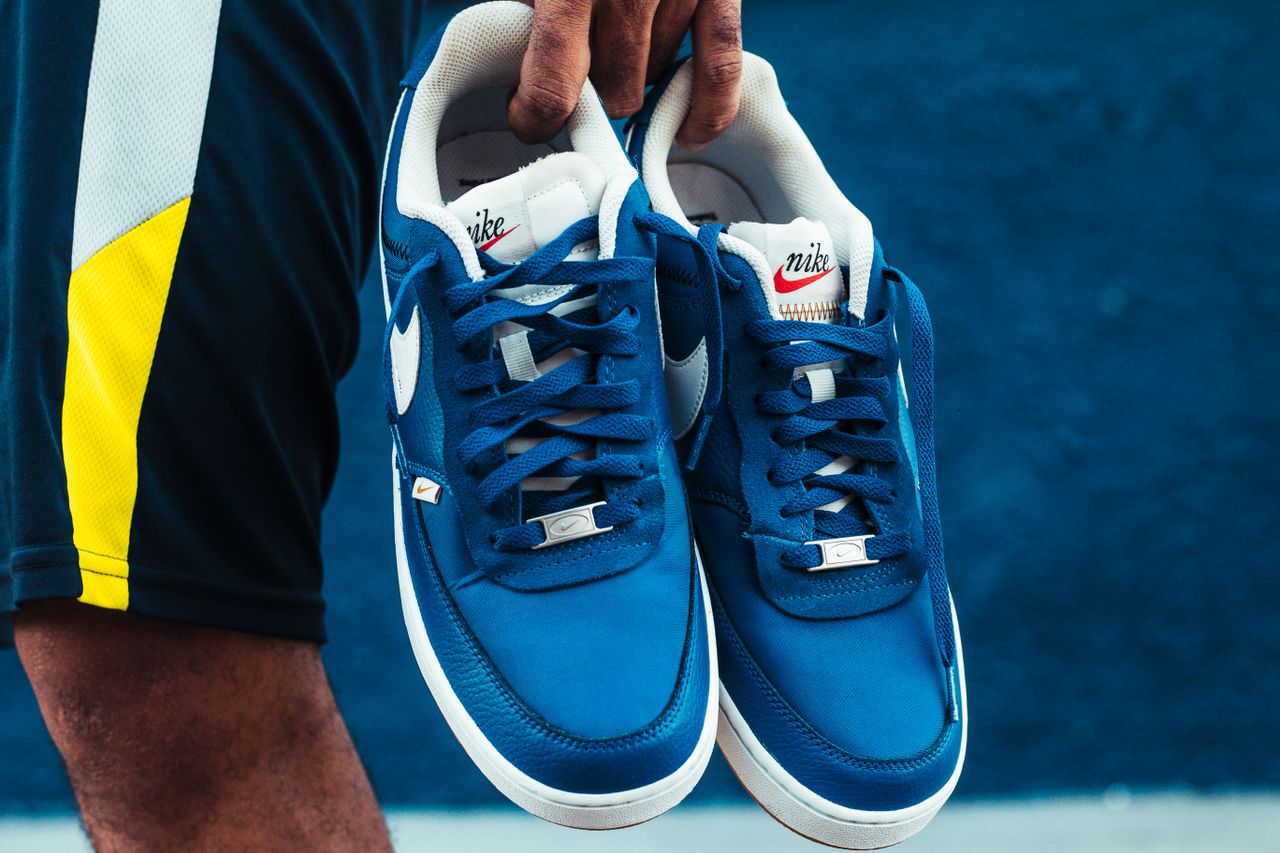 Services Detailed view of blue Nike sneakers being held outdoors, showcasing style and brand.