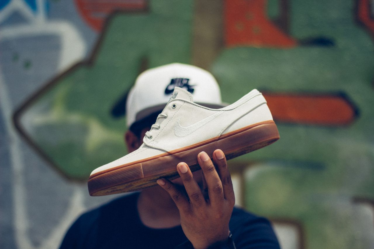 Mastering the First Impression: Your intriguing post title goes here Unrecognizable man in cap holding stylish white sneakers with rubber outsole in hand while standing against wall with graffiti