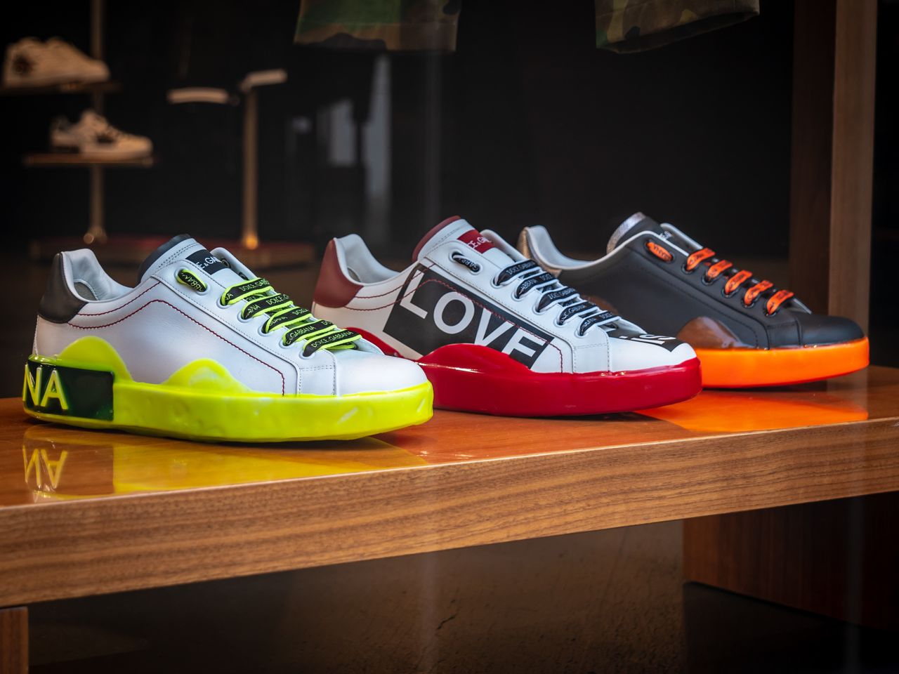 Services Vibrant colored sneakers displayed on a wooden table in a London store.