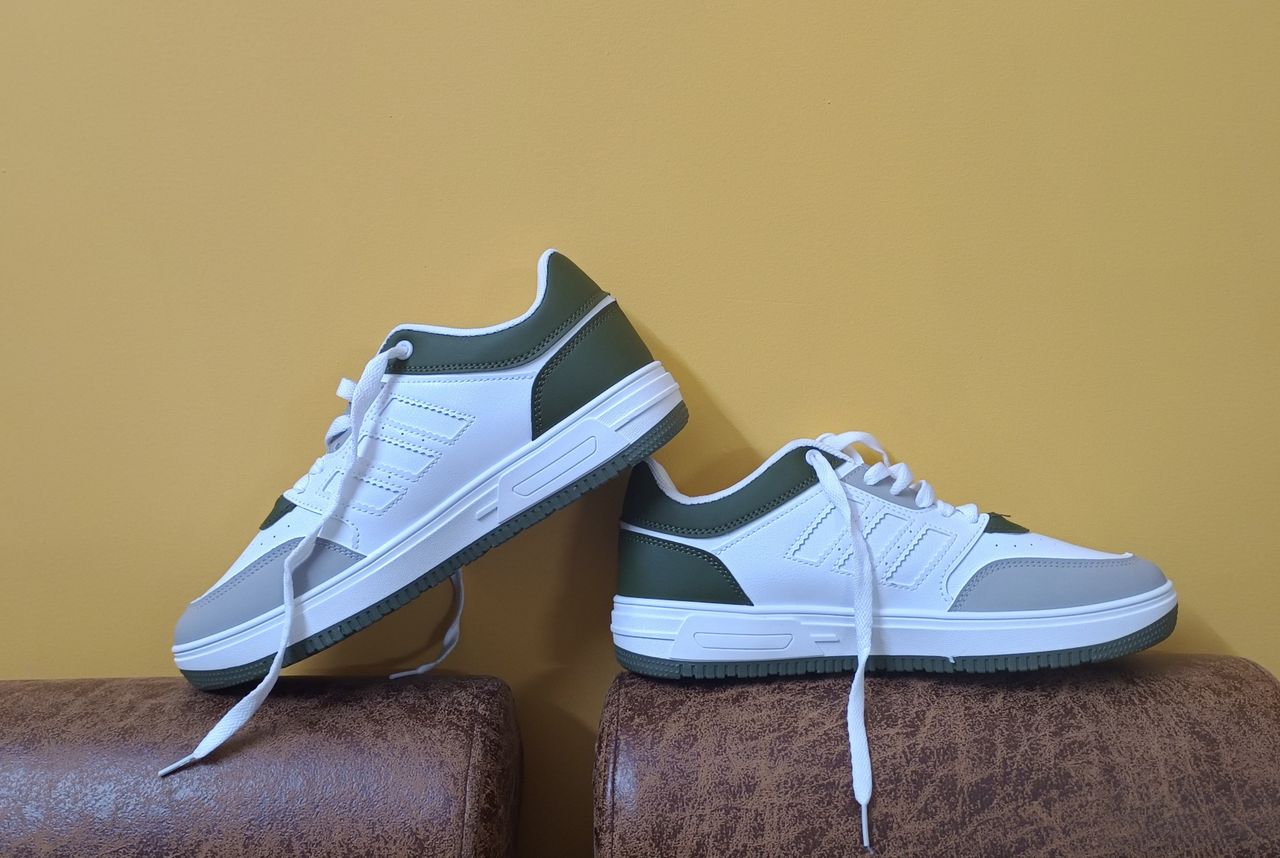 Crafting Captivating Headlines: Your awesome post title goes here White and green casual shoes elegantly displayed against a yellow backdrop, perfect for fashion concepts.