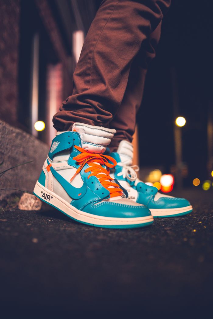 Services Close-up of vibrant high-top sneakers on a night-lit street, exuding urban style and streetwear fashion.